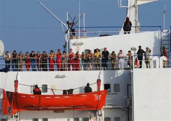 In this photo released by the United States Navy, the crew of the merchant vessel MV Faina stand on the deck of the ship, accompanied by Somali pirates, Sunday, Oct. 19, 2008 after a U.S. Navy request to check on the health and welfare of the ship's crew in the Indian Ocean off the coast of Somalia. The Belize-flagged cargo ship, owned and operated by Kaalbye Shipping, Ukraine, was seized by pirates Sept. 25 and forced to proceed to anchorage off the Somali Coast. The ship is carrying a cargo of Ukrainian T-72 tanks and related military equipment. Pirates holding pirates the ship have demanded an $8 million ransom.